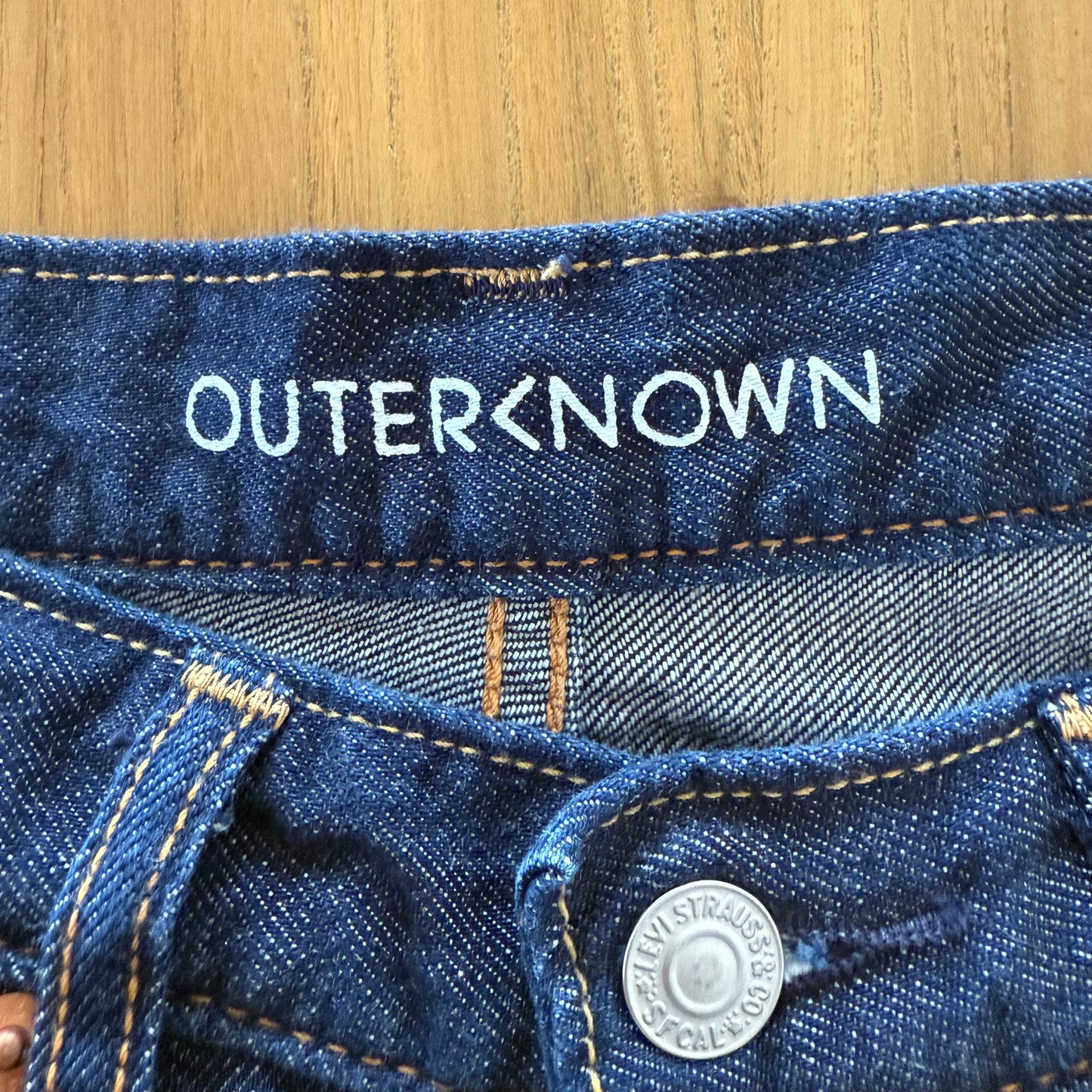 Close-up of Outerknown collaboration branding on blue Levis 511 jeans.