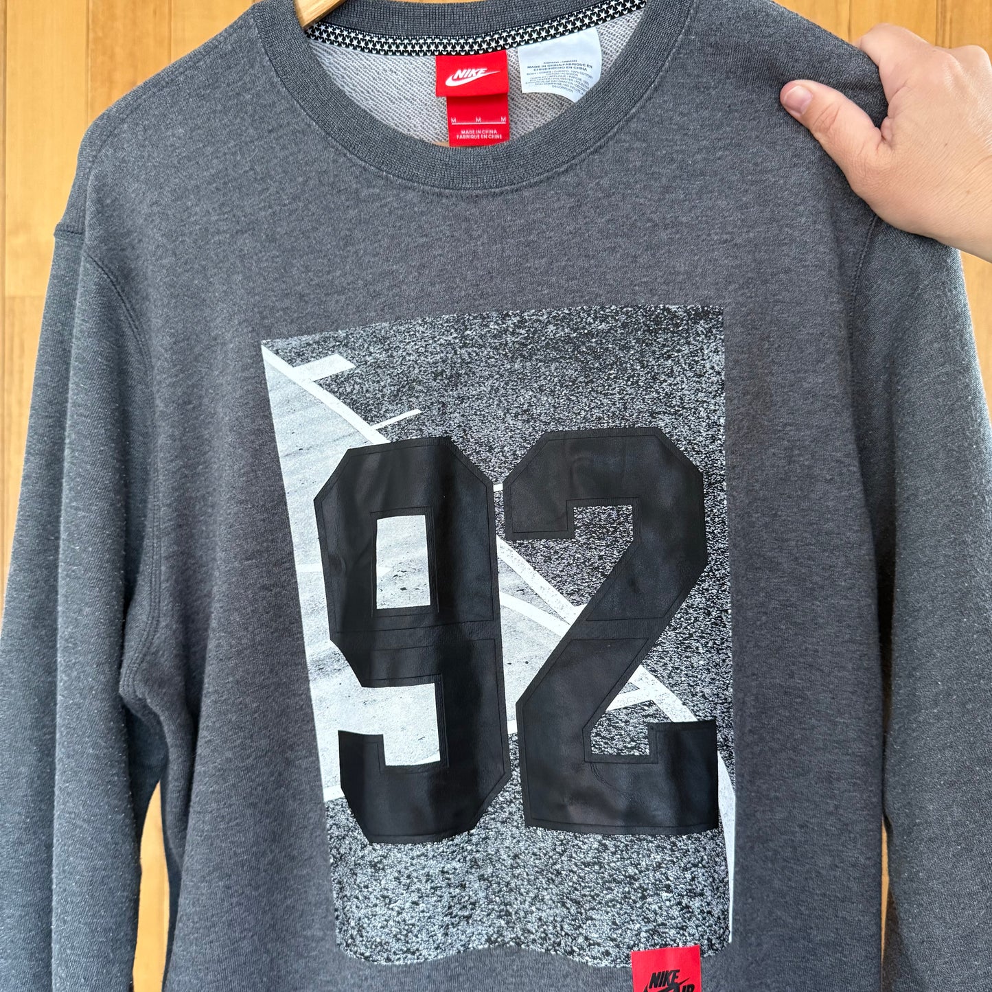 Close-up detail of multicolor print on Nike Air 92 grey crew sweatshirt in worn condition