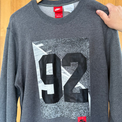 Close-up detail of multicolor print on Nike Air 92 grey crew sweatshirt in worn condition