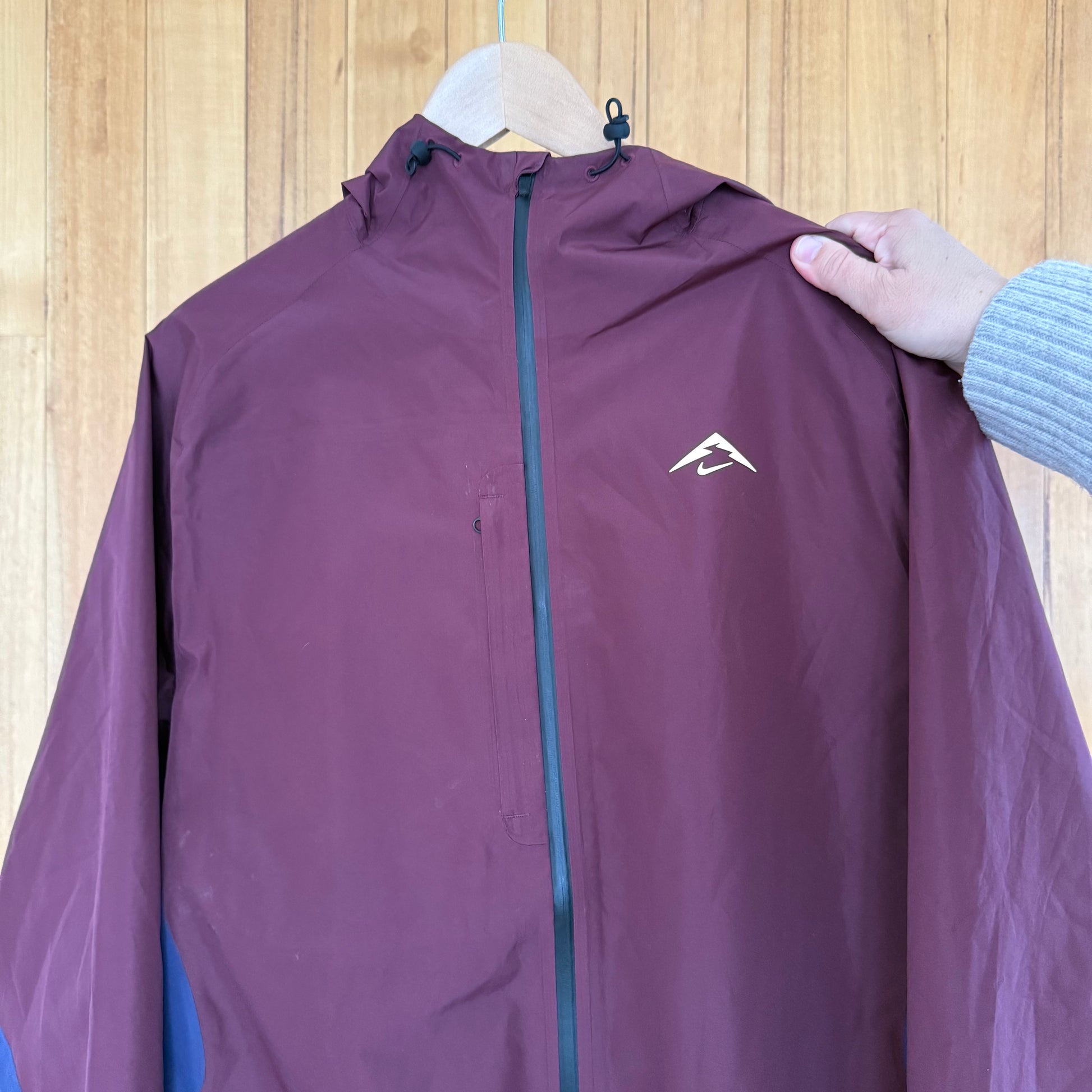 Nike Trail logo detail on maroon and navy Cosmic Peaks Gore-Tex jacket